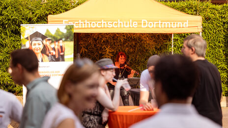 Eindrücke vom Sommerfest 2024. Geigerin steht unter einem Zelt mit der Aufschrift Fachhochschule Dortmund.