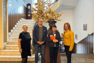 Vier Personen stehen in einem repräsentativen Treppenhaus.