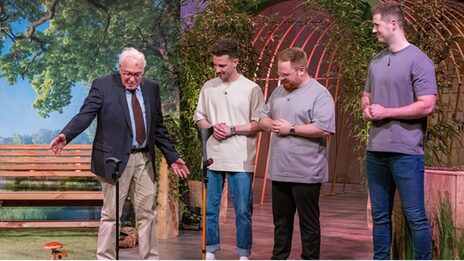 Ein älterer Mann zeigt, wie sein Gehstock allein stehen bleibt. Drei junge Männer schauen dabei zu.