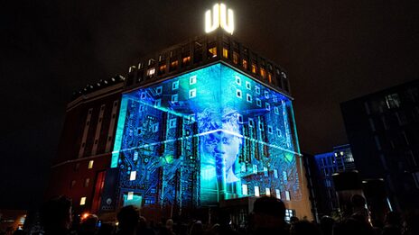Die Fasse des Gebäudes Dortmunder U wird vor dunklem Himmel mit verschiedenen Motiven angestrahlt.