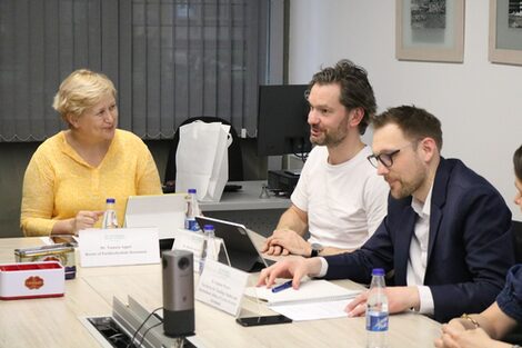 Menschen sitzen an einem Tisch und besprechen sich.