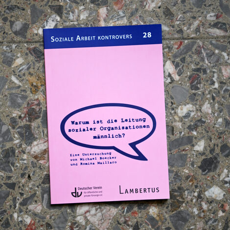 A book with the title "Why is the management of social organizations male?" lies on a stone floor.