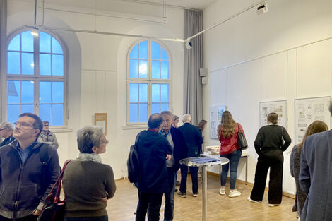 View of an exhibition room in the Hoesch Museum with visitors looking at the design plans on the wall.