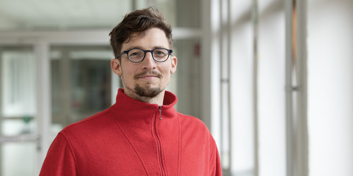 Eine Person im roten Pullover schaut freundlich in die Kamera.