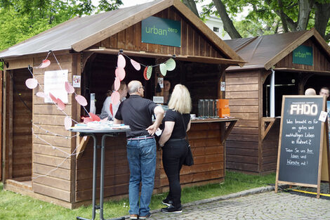 Two people gather information at an information stand. The display shows that the stand belongs to Fachhochschule Dortmund.