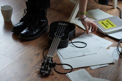 A ukulele lies on the floor next to various song lyrics