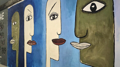 A picture on a section of the Wall in Berlin. It shows white and black heads.
