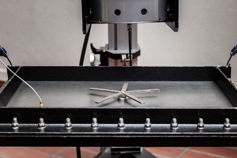 Photo of a metal star on a plate that is excited by electrically operated oscillators.