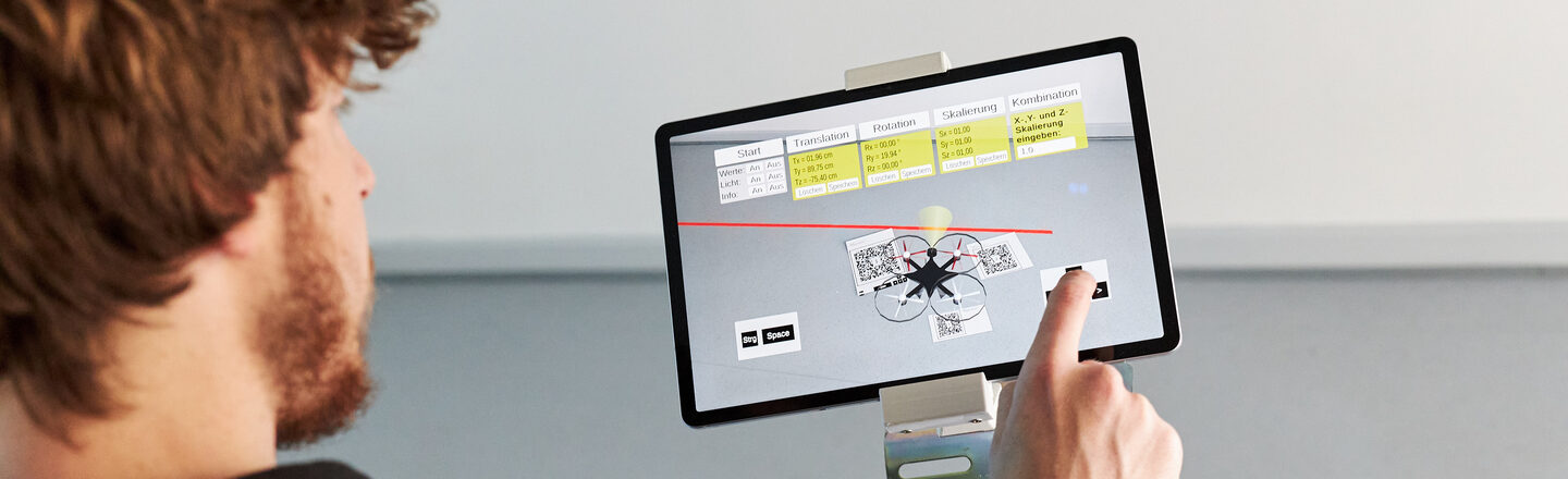 Foto von einer Person, die eine virtuelle Drohnen an einem Tablet steuert.