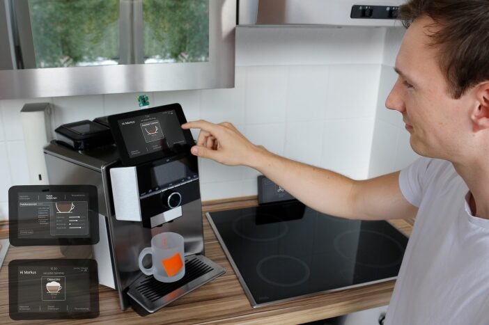 Smarte Kaffeemaschine als Haushaltsassistent, die ein junger Mann bedient.