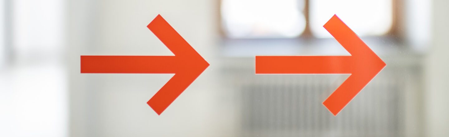 Photo of two orange arrows on a glass door.