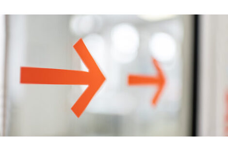 Photo of two orange arrows on a glass door.