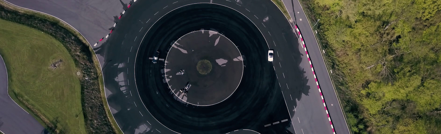 Bird's eye view of a circular track with irrigation. Test vehicles (Volvo, Spyder) are driving on it.