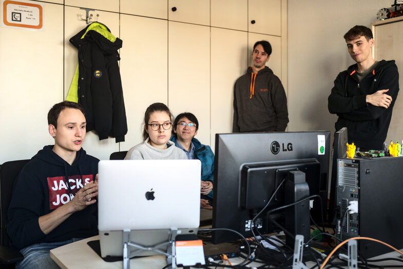 The team spokespersons sit in front of two monitors and discuss the next steps with the professors of the robotics group who are connected in an online meeting