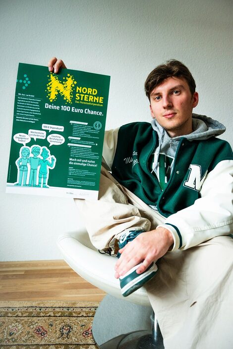 Der duale Student Miguel Fraczek zeigt ein Plakat des Nordsterne-Stipendiums
