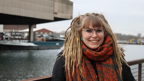 Sabrina Günther smiles into the camera. In the blurred background, a barge sails across the Dortmund-Ems Canal.