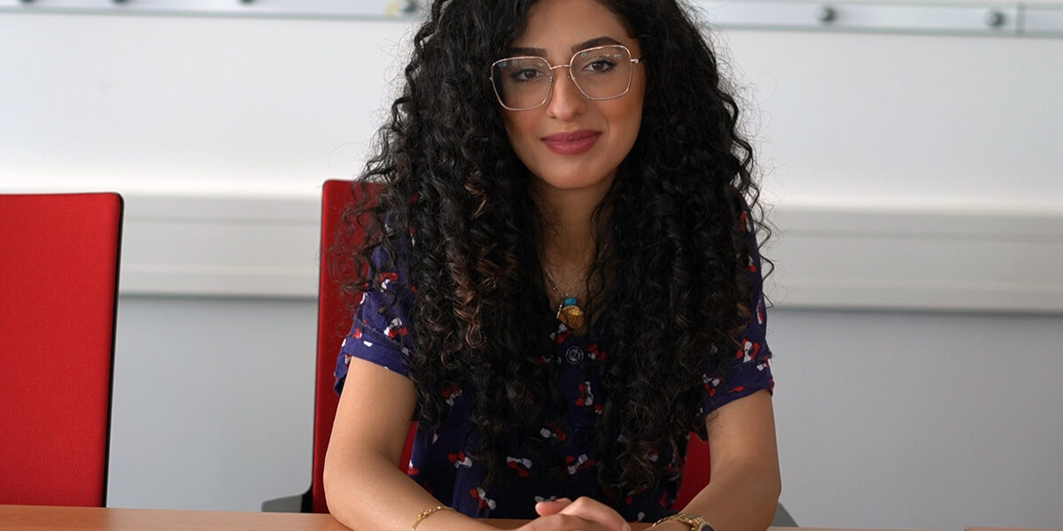 Porträtfoto, das Sedra Dayoub an einem Tisch sitzend zeigt