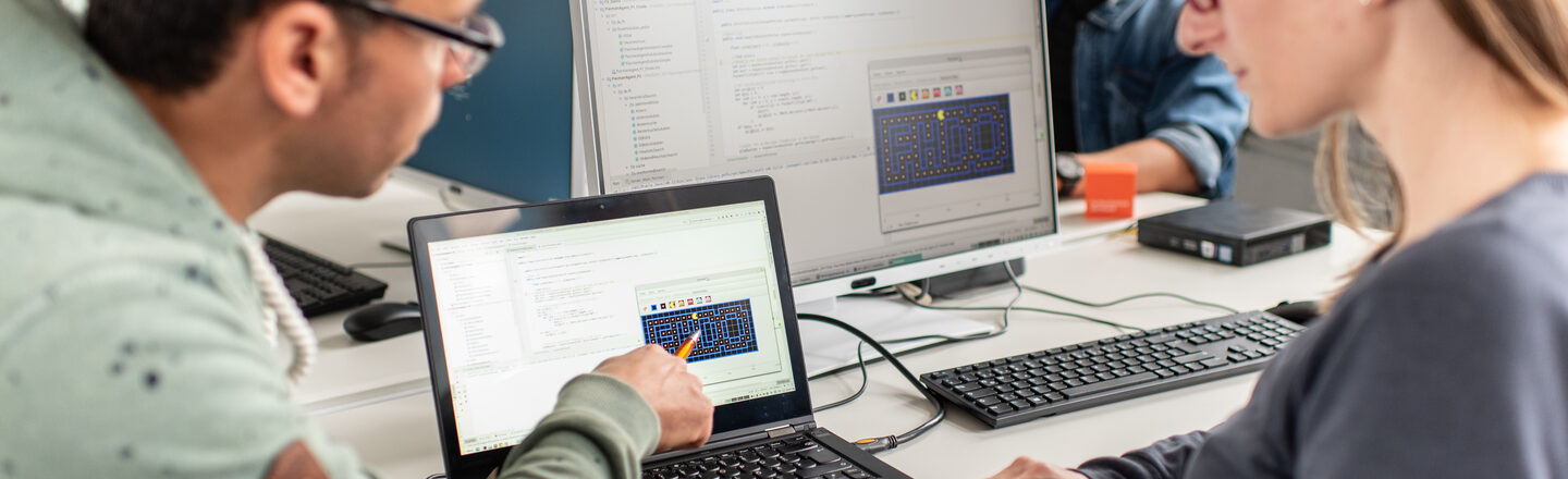 Photo of an employee showing his colleague something on his laptop.