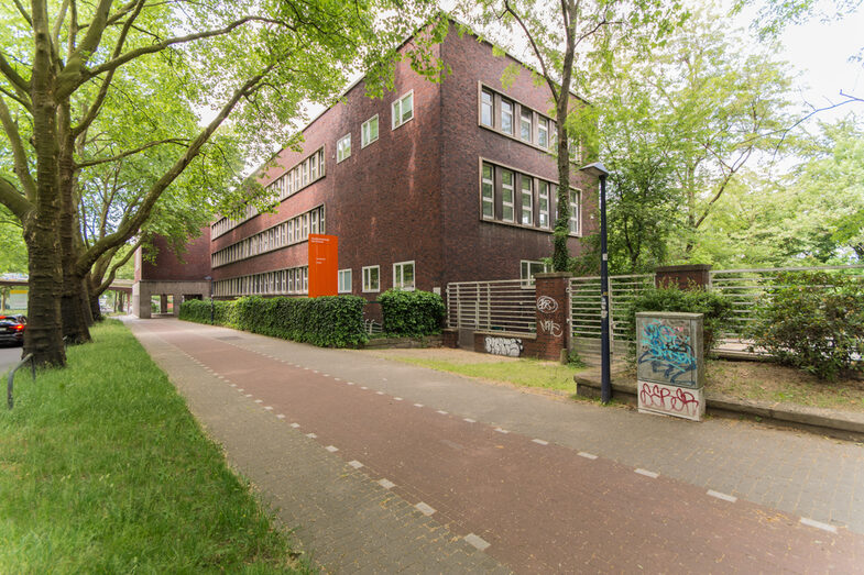 Photo with a view of a Fachhochschule Dortmund building on Max-Ophüls-Platz with a pedestrian path and cycle path in front of it.