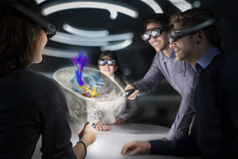Vier junge Menschen sehen sich durch eine Virtual Reality Brille den Querschnitt eines menschlichen Schädels mit verschiedenen anatomischen Strukturen an.