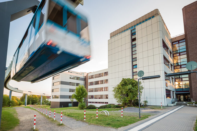 Foto des Gebäude Emil-Figge-Straße 44. Links im Bild die H-Bahn-Schienen mit vorbeifahrender H-Bahn.