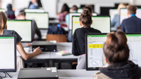 Blick von hinten in den Computerraum mit Studierenden, auf den Monitoren sind zum Teil Excel-Tabellen erkennbar.