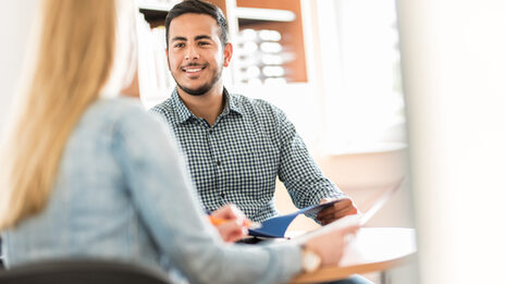 Photo of a young man being advised by a Career Service employee about his application portfolio.