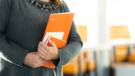 Foto einer Frau - kopfabwärts - mit Unterlagen in den Händen. __ Woman with documents in her hands.