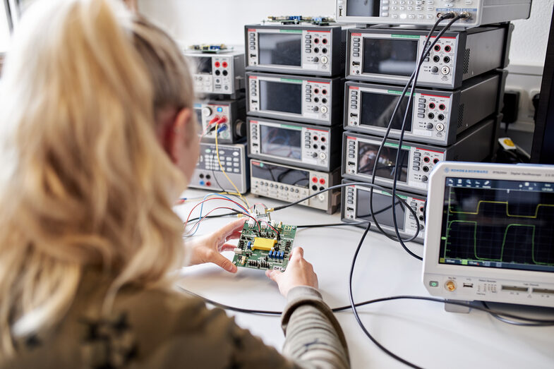 Auf dem Bild sieht man eine Person, die einen Chip hochkant in den Händen hält, damit die Fotodiode auf den Lichteinfall reagiert und die entstehenden Frequenzen gemessen werden können.