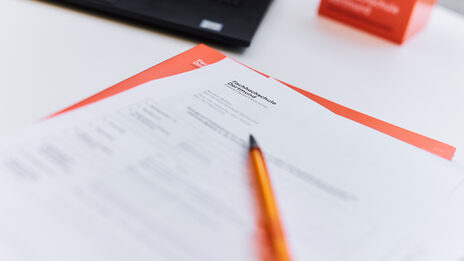 Photo of documents with the caption "Fachhochschule Dortmund" and a ballpoint pen on a table.