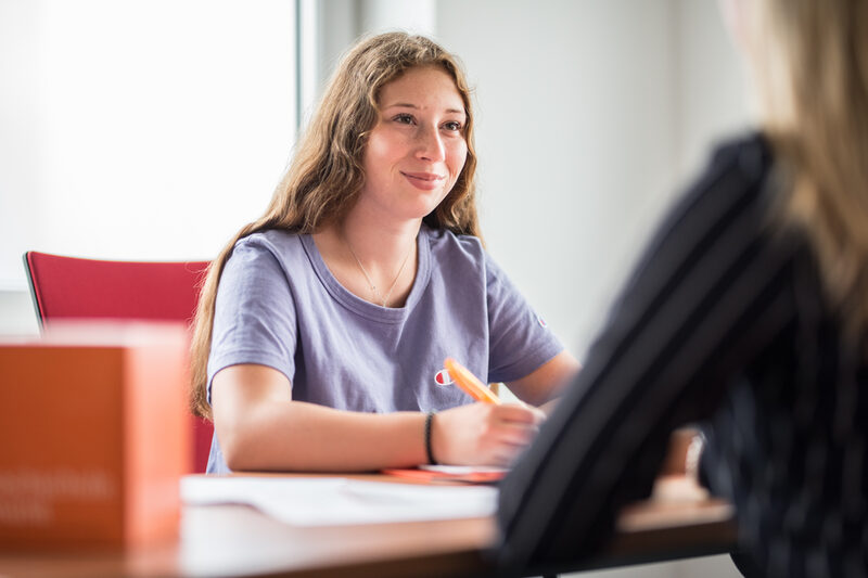 Photo of a student sitting opposite another woman, who can only be seen in the crop on the right of the picture. They are having a student counseling interview.