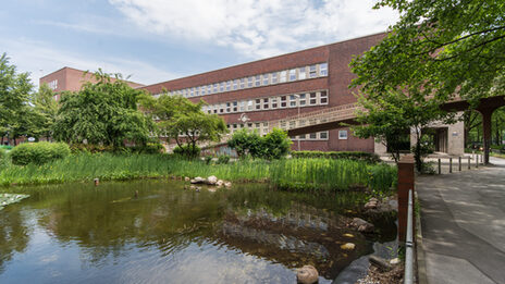 Foto mit Blick über einen Teich hin zum Gebäude des Fachbereichs Design am Max-Ophüls-Platz.
