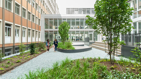 Photo of the inner courtyard at the student workplaces on Sonnenstraße. Two women are walking in the courtyard.