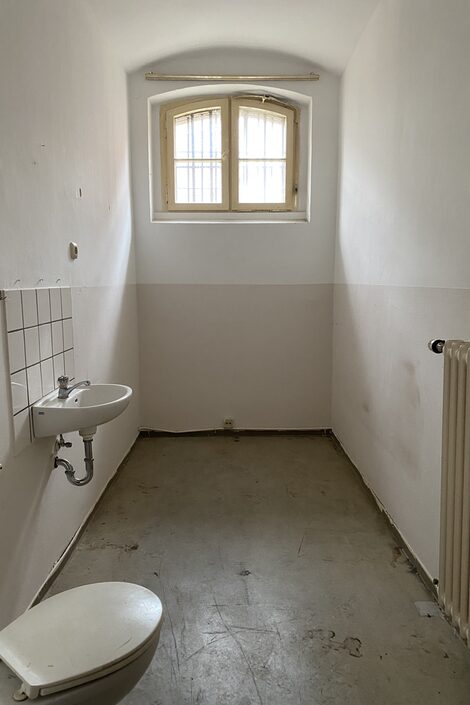 Blick aus der Eingangstür in eine leere Gefängniszelle