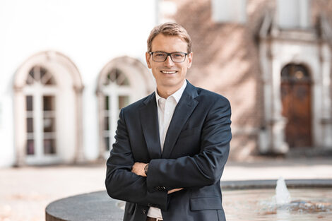 A man stands smiling in front of a building.