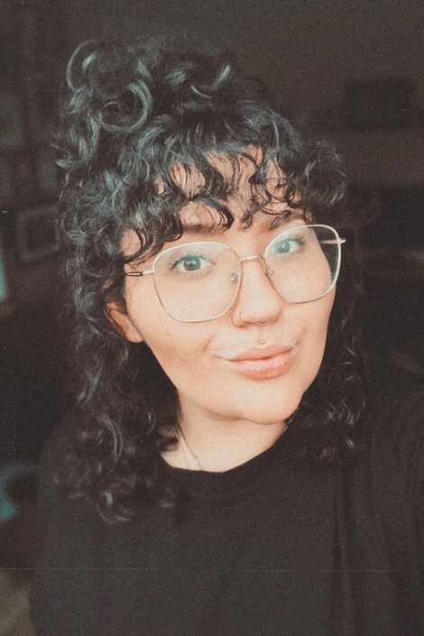 a smiling woman with glasses and curly hair