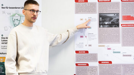 Eine Person in hellem Pullover deutet auf ein grafisch gestaltetes Poster mit der Überschrift „Netflix“.