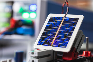Detailaufnahme einer quadratischen Solarzelle mit abgehenden Kabeln.