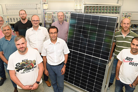Ein Gruppe von neun Personen stehen in einem Labor der FH Dortmund um ein Solarpanel.