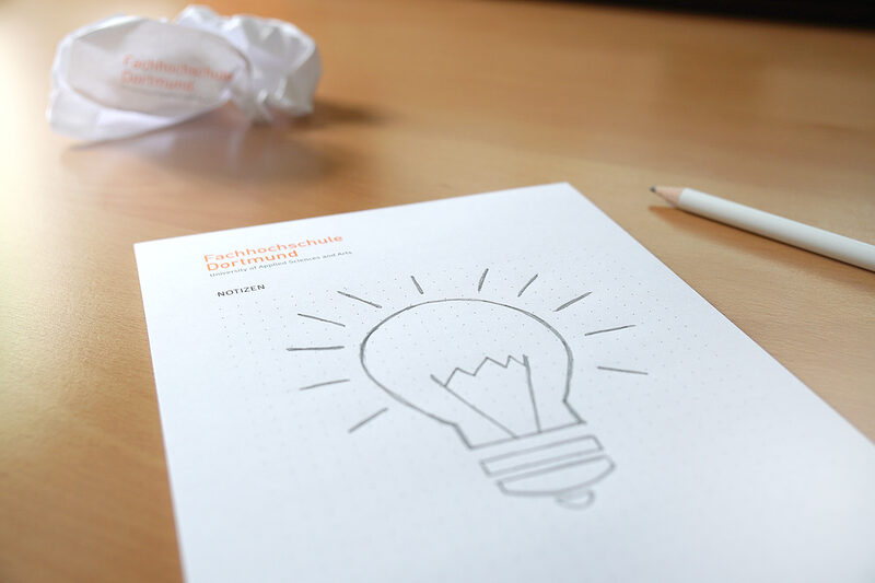 Photo of a sketch of a light bulb on a FH block, crumpled paper in the background and a FH pencil. __ Sketch of a light bulb on a FH block, crumpled paper in the background and a FH pencil.