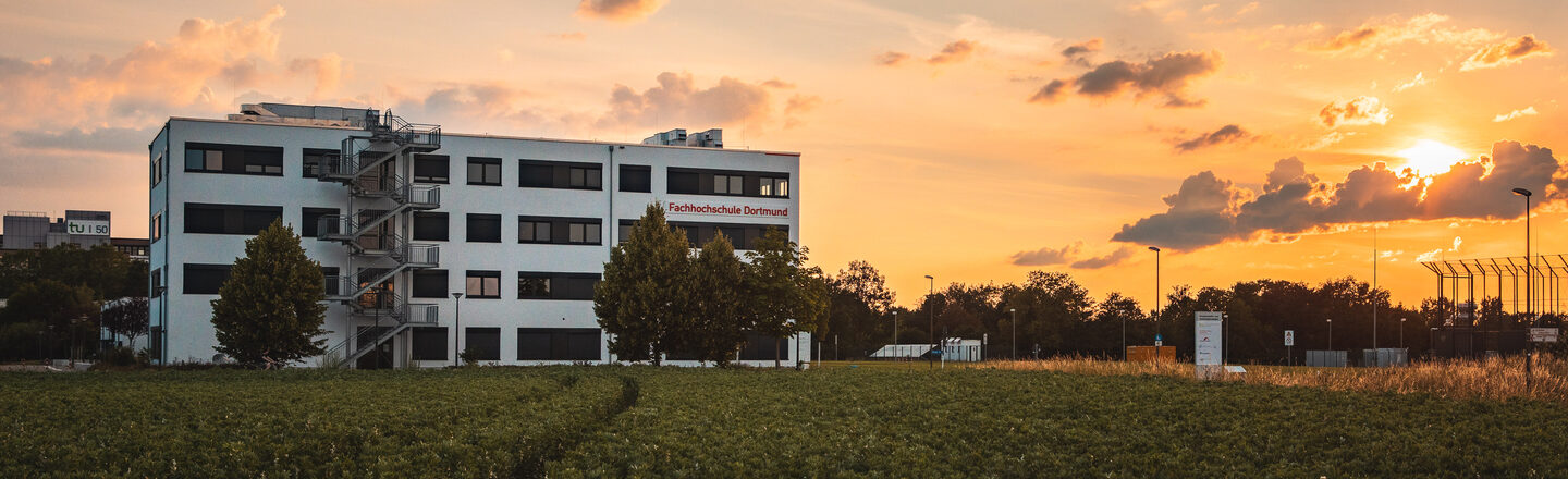Foto vom Gebäude Emil-Figge-Straße 38b der Fachhochschule Dortmund aus der Ferne mit beginnendem Sonnenuntergang.
