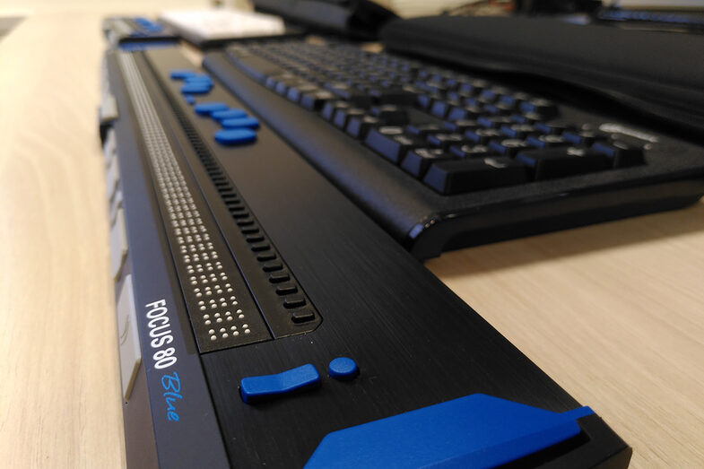 Close-up of a desk with a keyboard and a Braille display in front of it for tactile Braille.