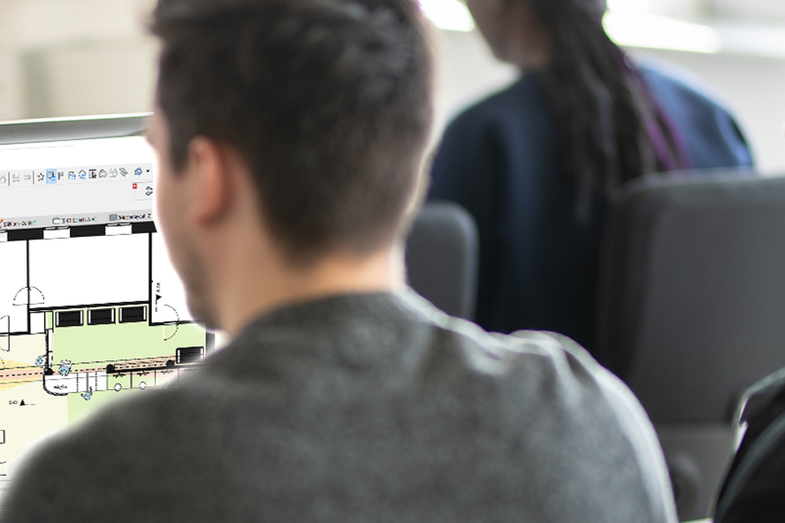 The picture shows two students from behind, sitting at a screen. A floor plan can be seen on the screen.