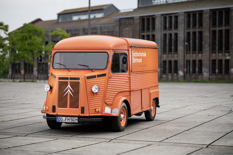 Photo of orange vintage van with FH logo in front of Warsteiner Music Hall. __ Orange Oltimer with FH logo in front of Warsteiner Music Hall.