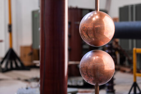 Photo of part of a spherical spark extender. You can see two large copper-colored spheres with a gap between them __.