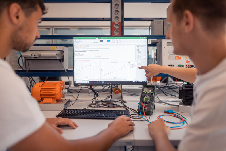 Foto von zwei Studierenden, im Labor, die Messungen an einem Monitor besprechen.