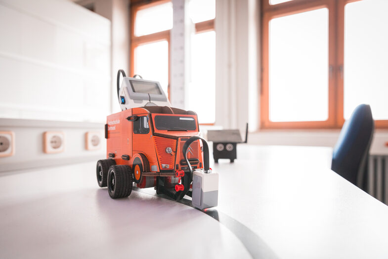 Foto von einem Lego Mindstorm in der Hülle der Citroen HY_Stiftebox. Dieser Roboter soll entlang einer schwarzen Linie fahren. Im Hintergrund ist ein Parksensor.