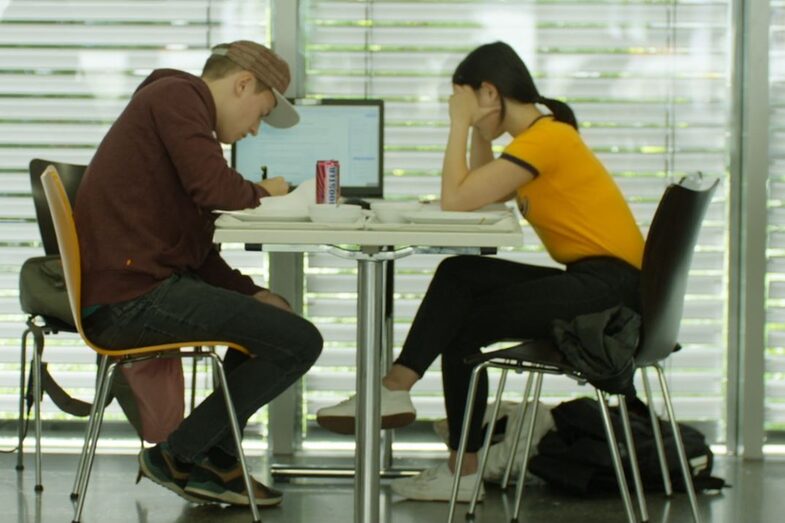Foto von 2 Studierenden, die am Tisch sitzen und lernen.
